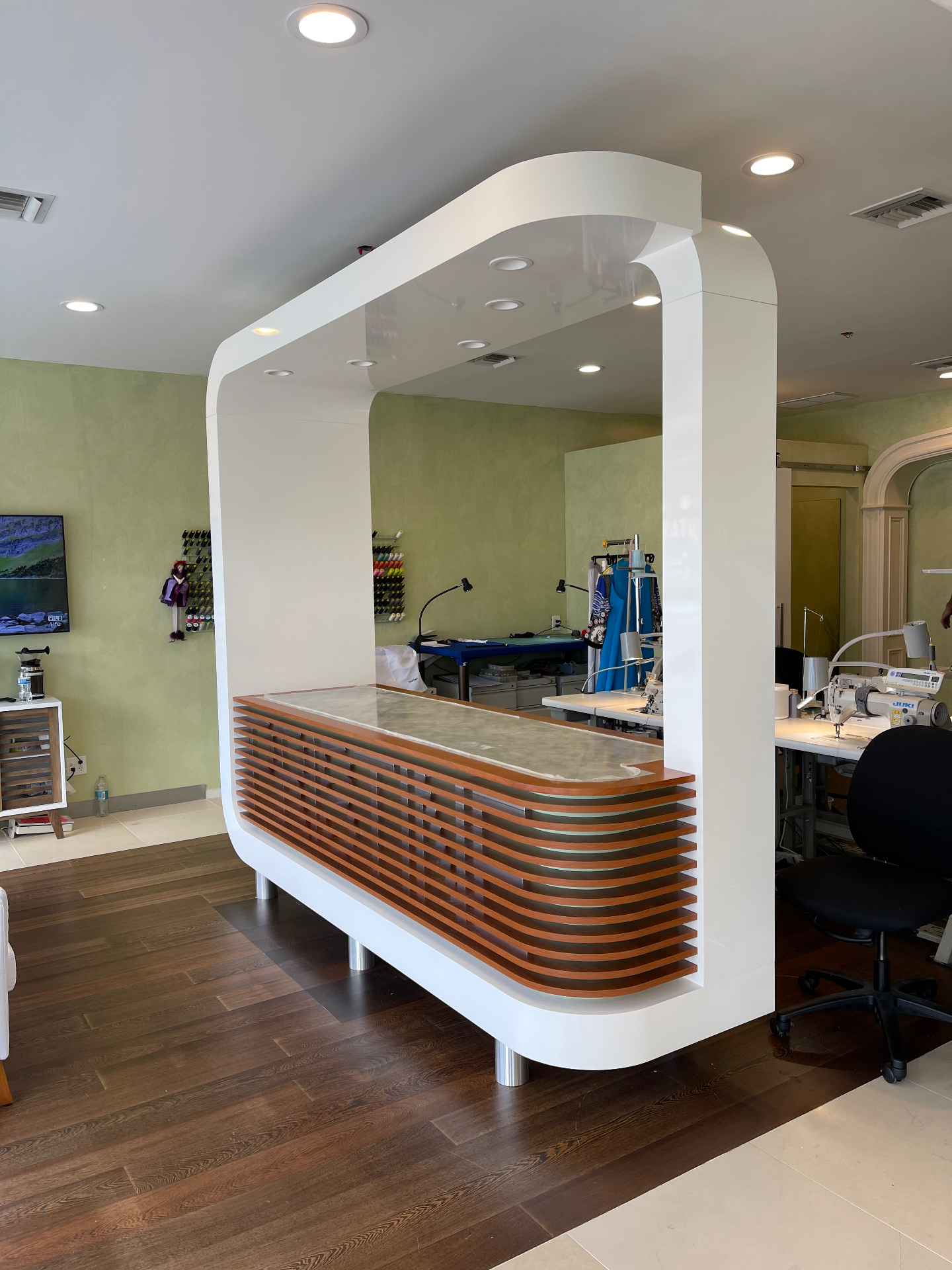 Curved reception and work counter with slatted wood front by ARTEC Woodworkers in Naples, Florida