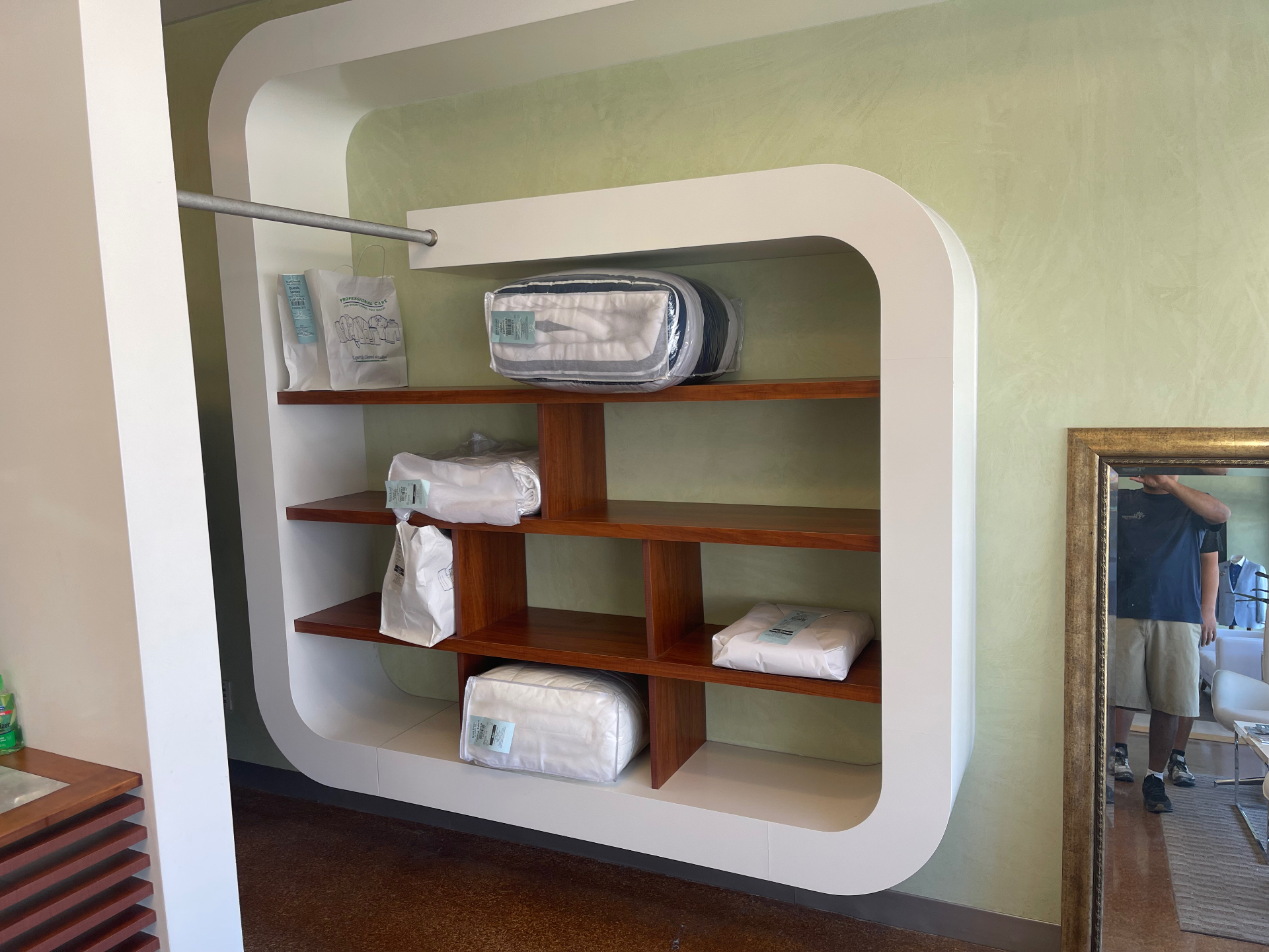 Custom display shelving in a rounded architectural frame with warm wood shelves by ARTEC Woodworkers