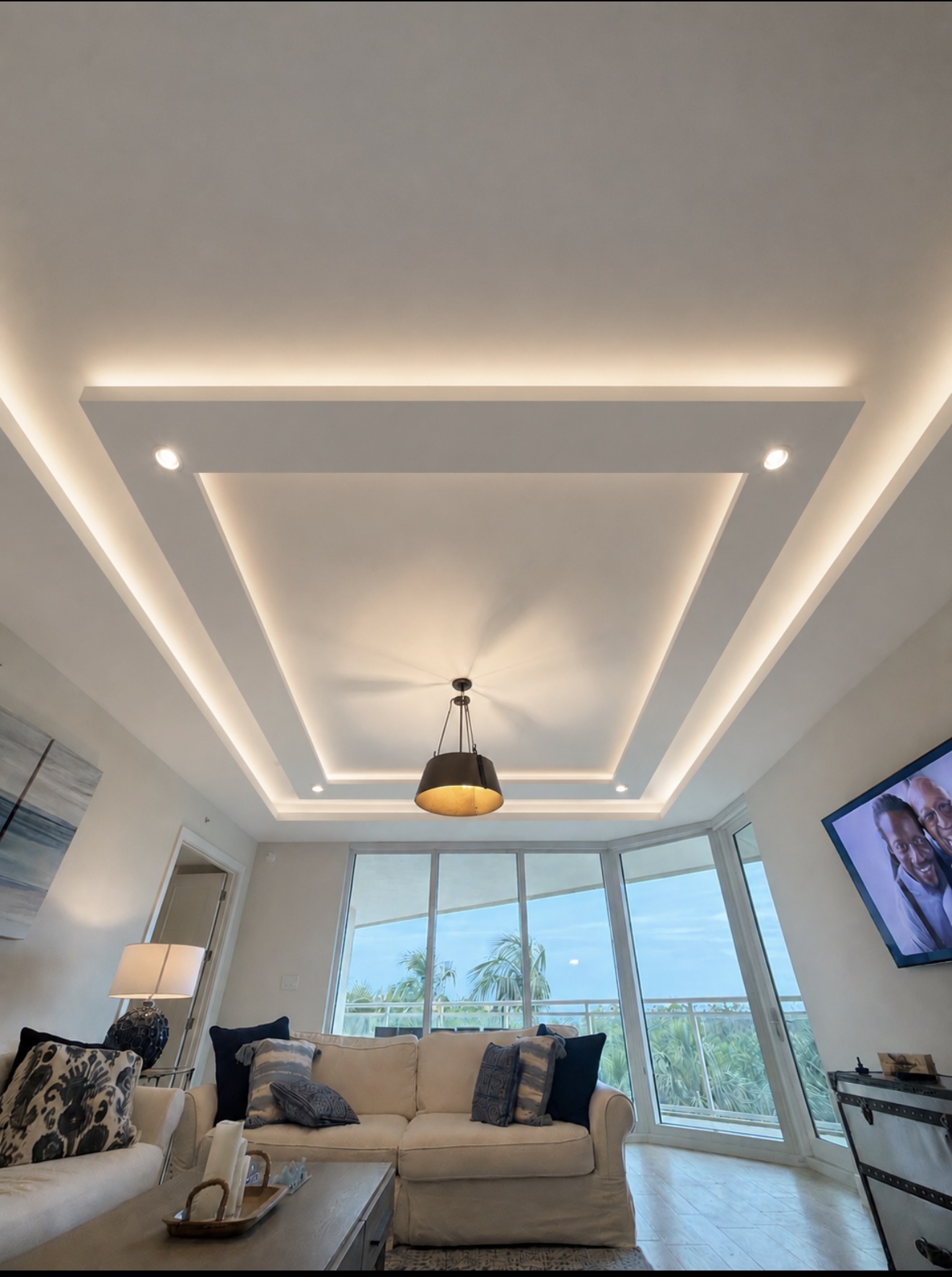 Living room with completed coffered ceiling millwork and concealed cove lighting