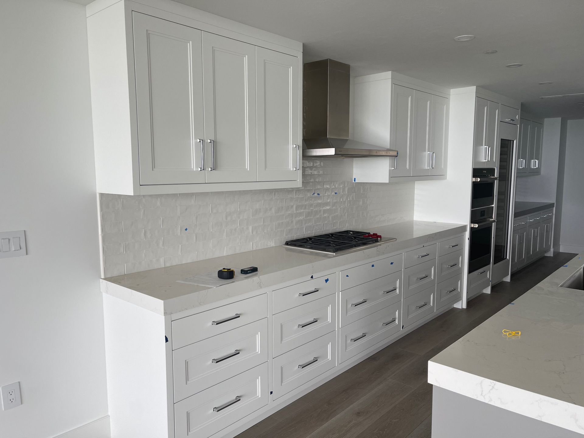 White cabinetry run with quartz countertop, deep drawer bank and integrated hood surround